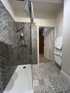 Walk in shower with grey tiles and white towels