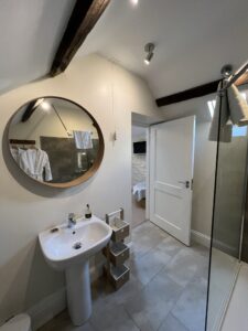 Walk in Shower with large circular mirror and white basin