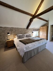 Superking bed with throw and cushions in high ceiling room with beams and original beams