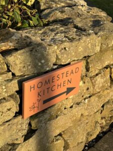 Painted Homestead Kitchen sign on a stone wall