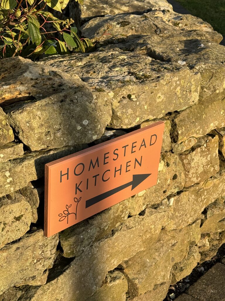 Painted Homestead Kitchen sign on a stone wall