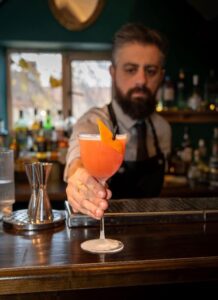 Bartender serving a stylist orance cocktail at bar