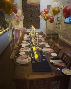 Dining table set for a birthday dinner with candles and balloons