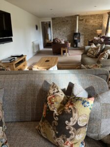 Living room with comfy wool sofas, cushions, throws and a wood burner