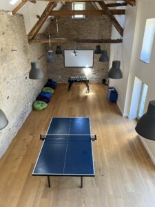 Barn with wooden floor set up with table tennis , table football and bean bags