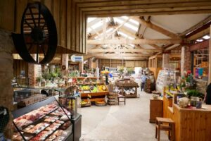 Inside of farm shop with butchers counter to left and fresh produce straight ahead.