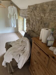 White towelling dressing gowns on a chair next to chest of drawers