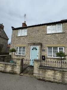 House with light blue door, railings and 3 faces carved into stone above front door