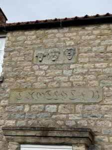 3 carved stone faces on house with inscription below