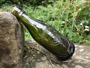 Green Glass bottle propped up against a stone wall