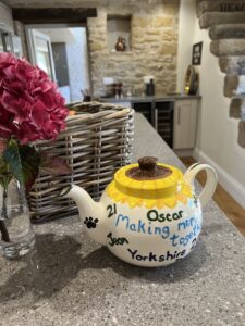 Decorated tea pot on kitchen island next to pink hydrangea.