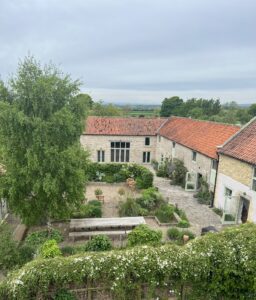 Aerial view of two barns surrounding a courtyard with large oak table and chairs.