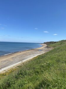 Sandy beech at Sandsend with green grass in foreground. 