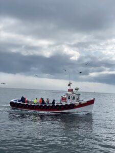 Fishing boat wih people in colourful jackets on board