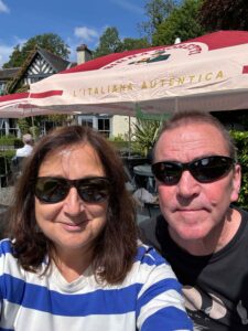 Woman in blue and white stripey top and man both wearing sunglasses and smiling at camera