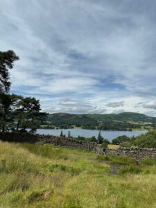 View down to lake from hillside with a stone wall in the foreground.