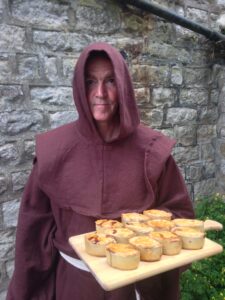 Man in monks outfit holdinga tray of pies