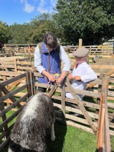 Small boy leaning on fence with woman looking at show stock