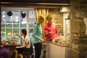 Male and female cyclists choosing cakes in a cafe in Rosedale