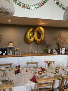 Gold 60 numbers over a side board in the dining room. Table set for a meal in front. 