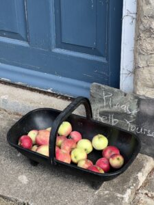 Basket of apples outside a front door with sign saying "help yourself"