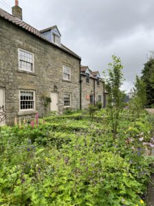 Stone Buildings with green cottage garden in front of them.