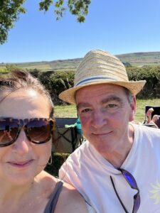 Man in straw hat and woman in sunglasses smiling at the camenra on a summers day