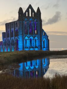 Whitby Abbey at sunset lit in blue and purple lights