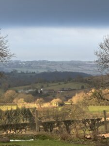 View over valley with winter sunlight on fields in foreground.