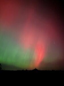 Red and green aurora above buildings