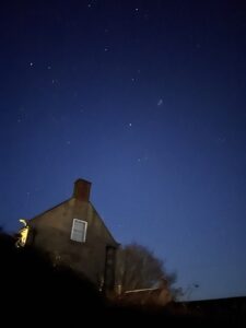 Dark blue night sky with lots of stars behind stone farm house