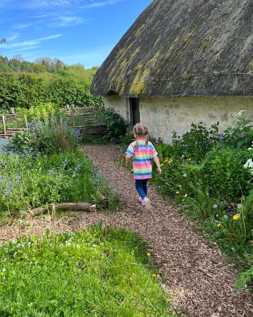 Little girl walking towards a thatched cottage in Ryedale Folk Museum
