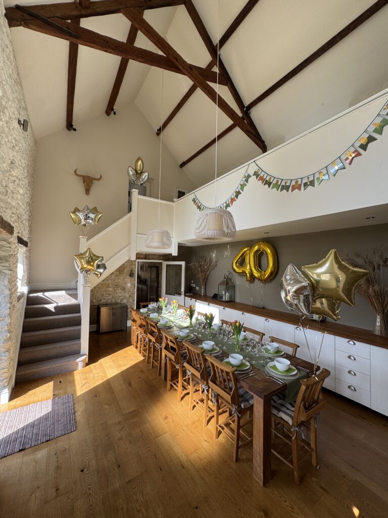 HIgh vaulted dining room in barn, with oak beans dressed with balloons and bunting for a 40th birthday.