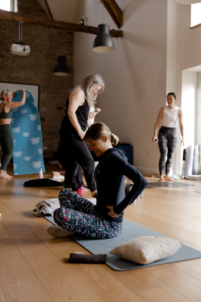 Woman sitting on yoga mat in class in Long Barn