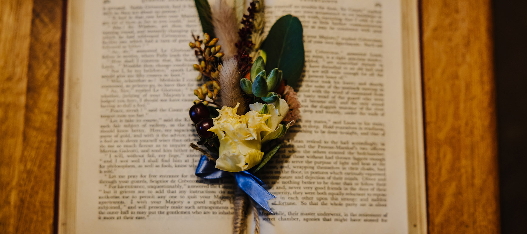Wedding buttonhole resting on an open book on a wooden surface