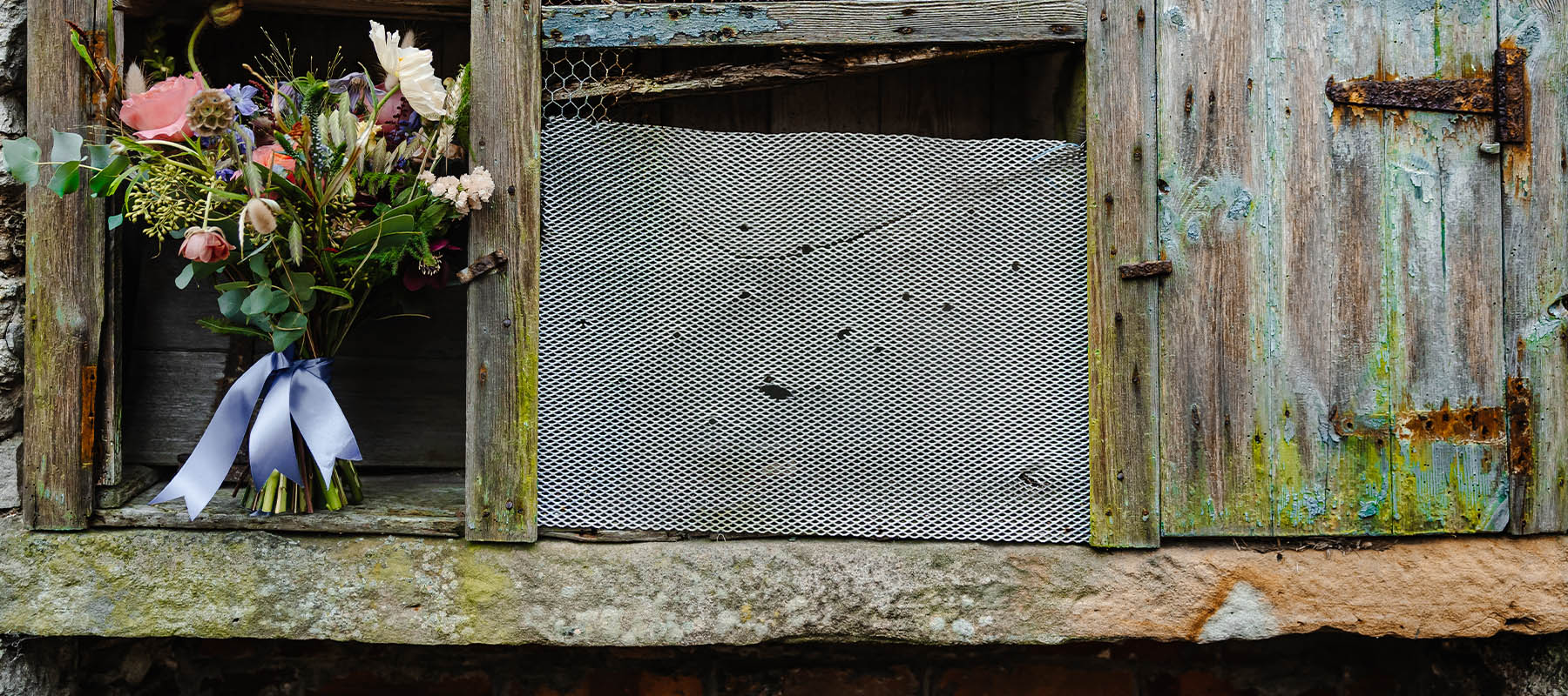 Bridal bouquet placed on a rustic barn window sill at the Long Barn